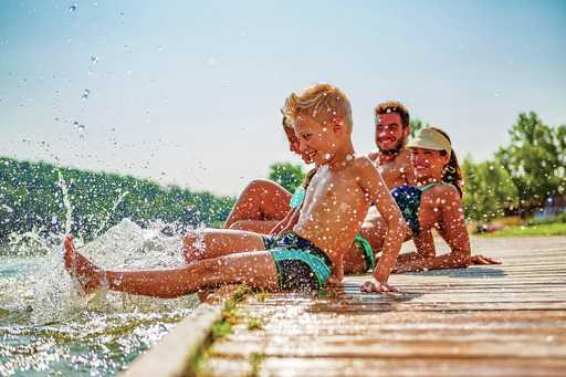 Family sitting on dock splashing in water